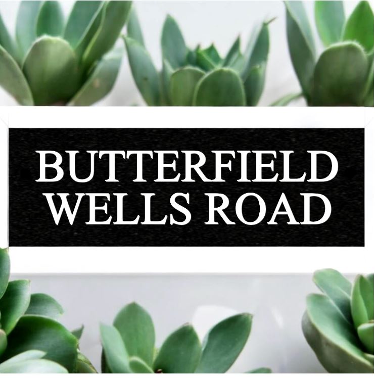 A black square House Sign with clear deep-cut numbers featuring a green plant placed elegantly on its surface www.HouseSign.co.uk