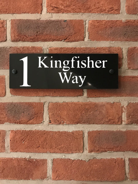 A black square House Sign with clear deep-cut numbers featuring a green plant placed elegantly on its surface www.HouseSign.co.uk