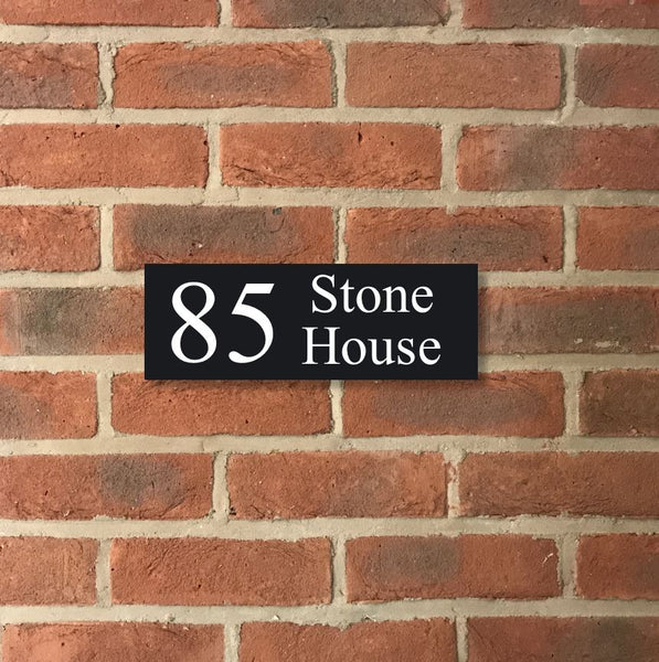 A black square House Sign with clear deep-cut numbers featuring a green plant placed elegantly on its surface www.HouseSign.co.uk