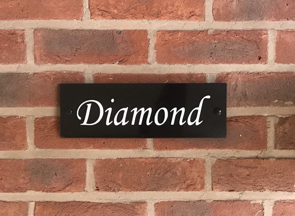 A black square House Sign with clear deep-cut numbers featuring a green plant placed elegantly on its surface www.HouseSign.co.uk