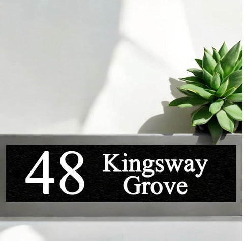 A black square House Sign with clear deep cut numbers featuring a green plant placed elegantly on its surface www.HouseSign.co.uk 