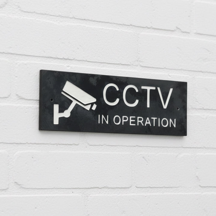 A CCTV Gate Or Wall Sign made in Natural Slate with polished edges and hard-wearing carved lettering size the sign has a camera logo 30cm x 10cm www.HouseSign.co.uk