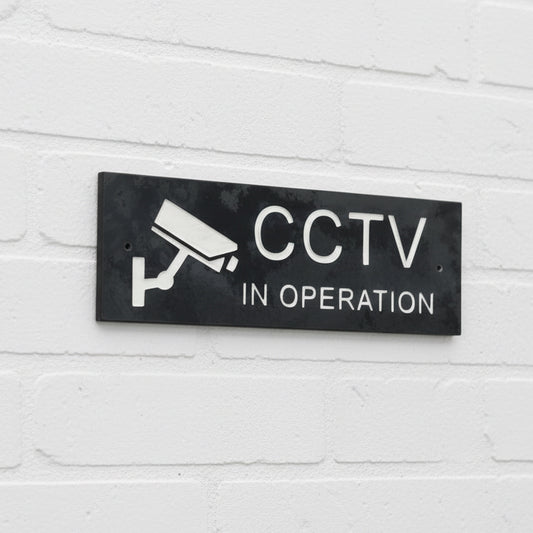 A CCTV Gate Or Wall Sign made in Natural Slate with polished edges and hard-wearing carved lettering size the sign has a camera logo 30cm x 10cm www.HouseSign.co.uk