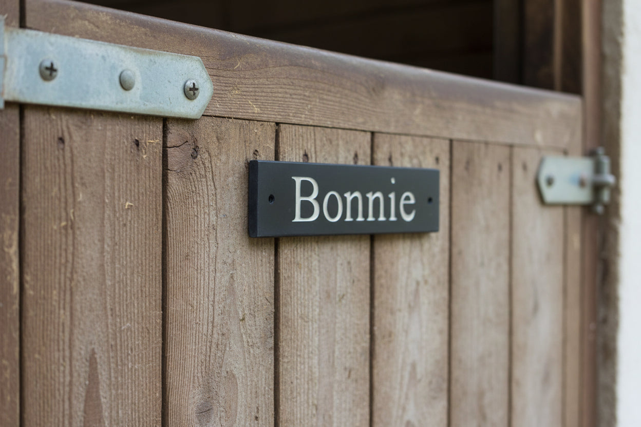 A sturdy stable slate sign with a prominently displayed stable horse name, indicating its purpose or providing information of a horse name to a passersby.