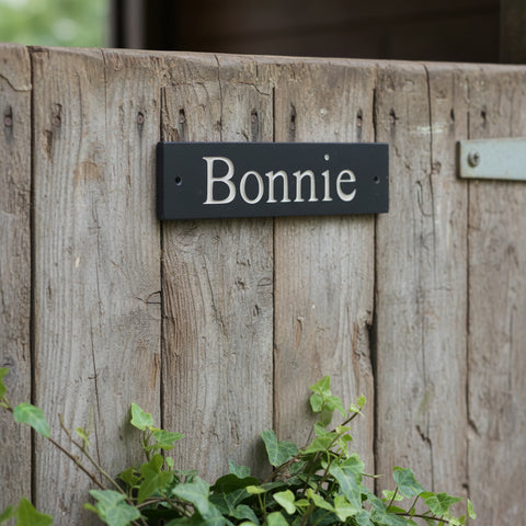 A sturdy stable slate sign with a prominently displayed stable horse name, indicating its purpose or providing information of a horse name to a passersby.
