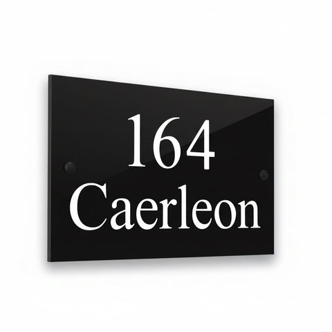 A black square House Sign with clear deep cut numbers featuring a green plant placed elegantly on its surface www.HouseSign.co.uk 