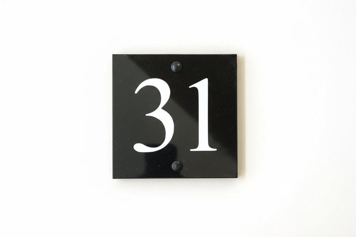 A black square House Sign with clear to see deep cut numbers featuring a green plant placed elegantly on its surface www.HouseSign.co.uk 