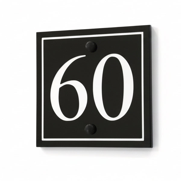 A black square House Sign with clear deep cut numbers featuring a green plant placed elegantly on its surface www.HouseSign.co.uk 