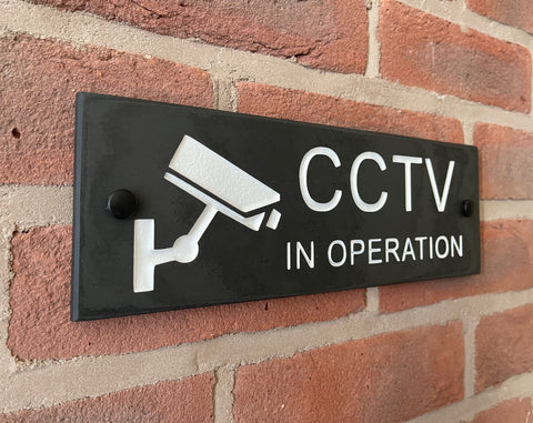 A CCTV Gate Or Wall Sign made in Natural Slate with polished edges and hard-wearing carved lettering size the sign has a camera logo 30cm x 10cm www.HouseSign.co.uk